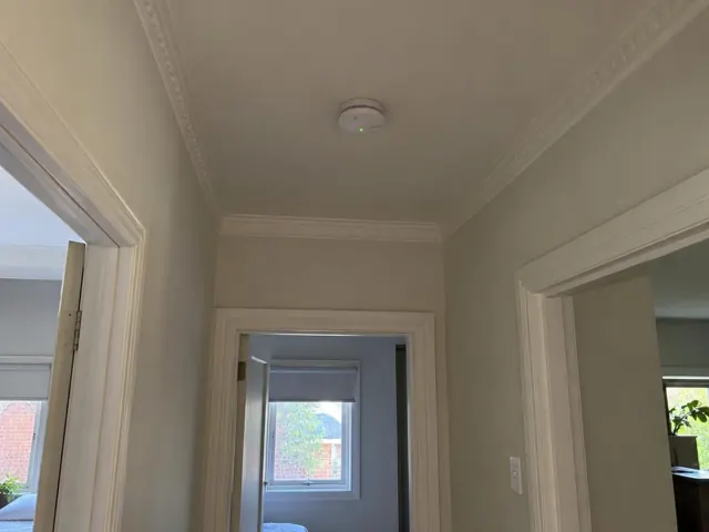 Hallway ceiling with a smoke alarm above doorways in a painted home interior in Marsfield